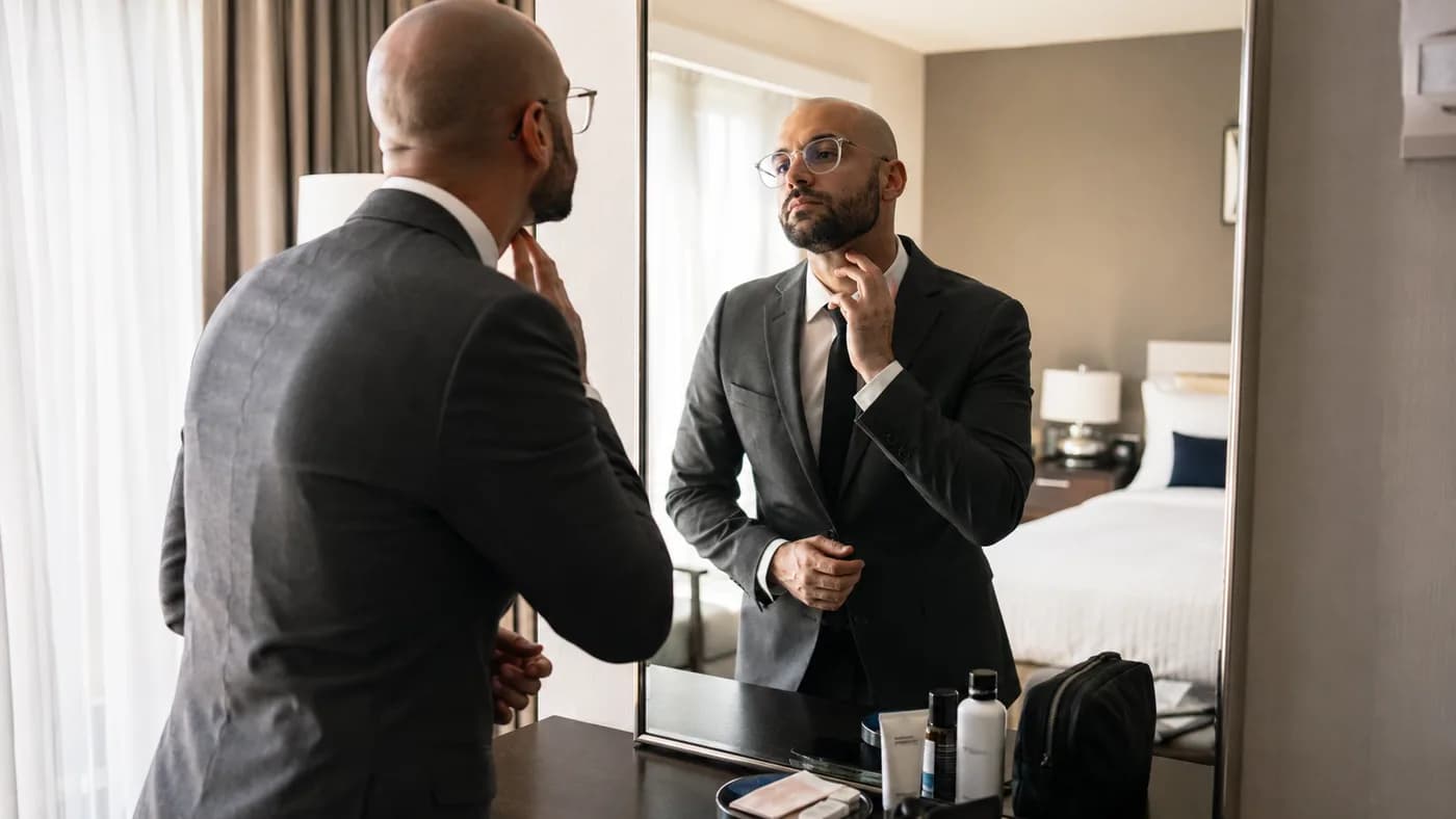 Bald wedding guest checking beard line and glasses before the event