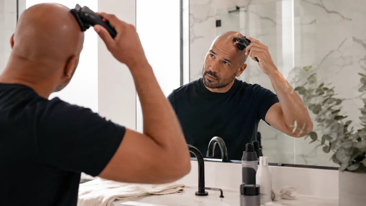 Bald man using an electric shaver during a simple scalp-care routine